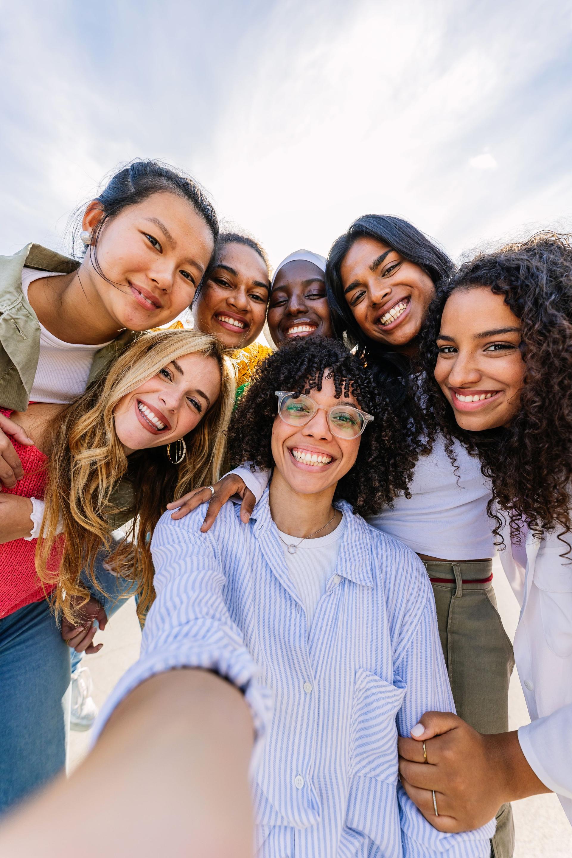 Diverse group of happy young best female friends having fun together outdoors.