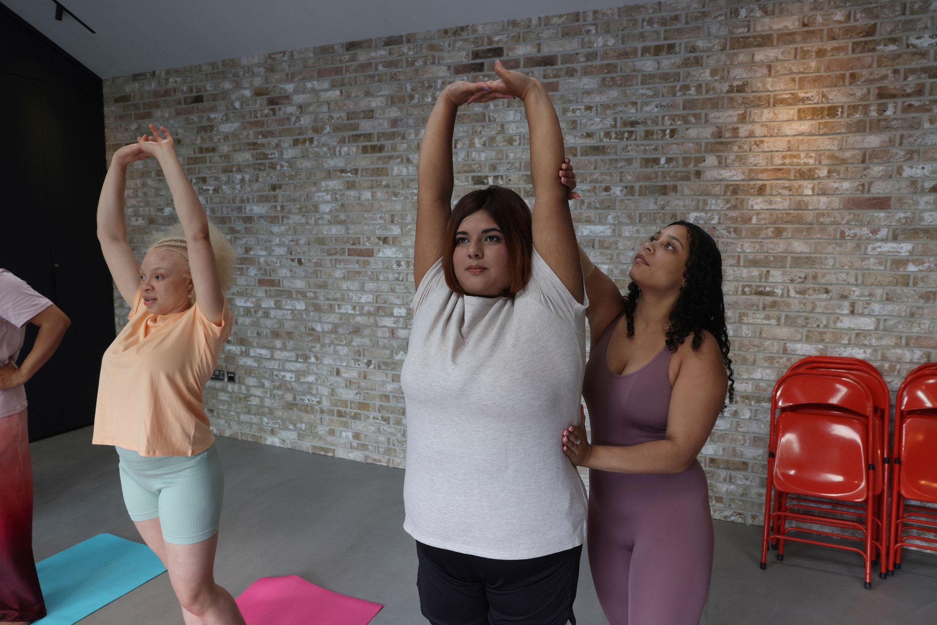Instructor assisting while students standing with arms raised