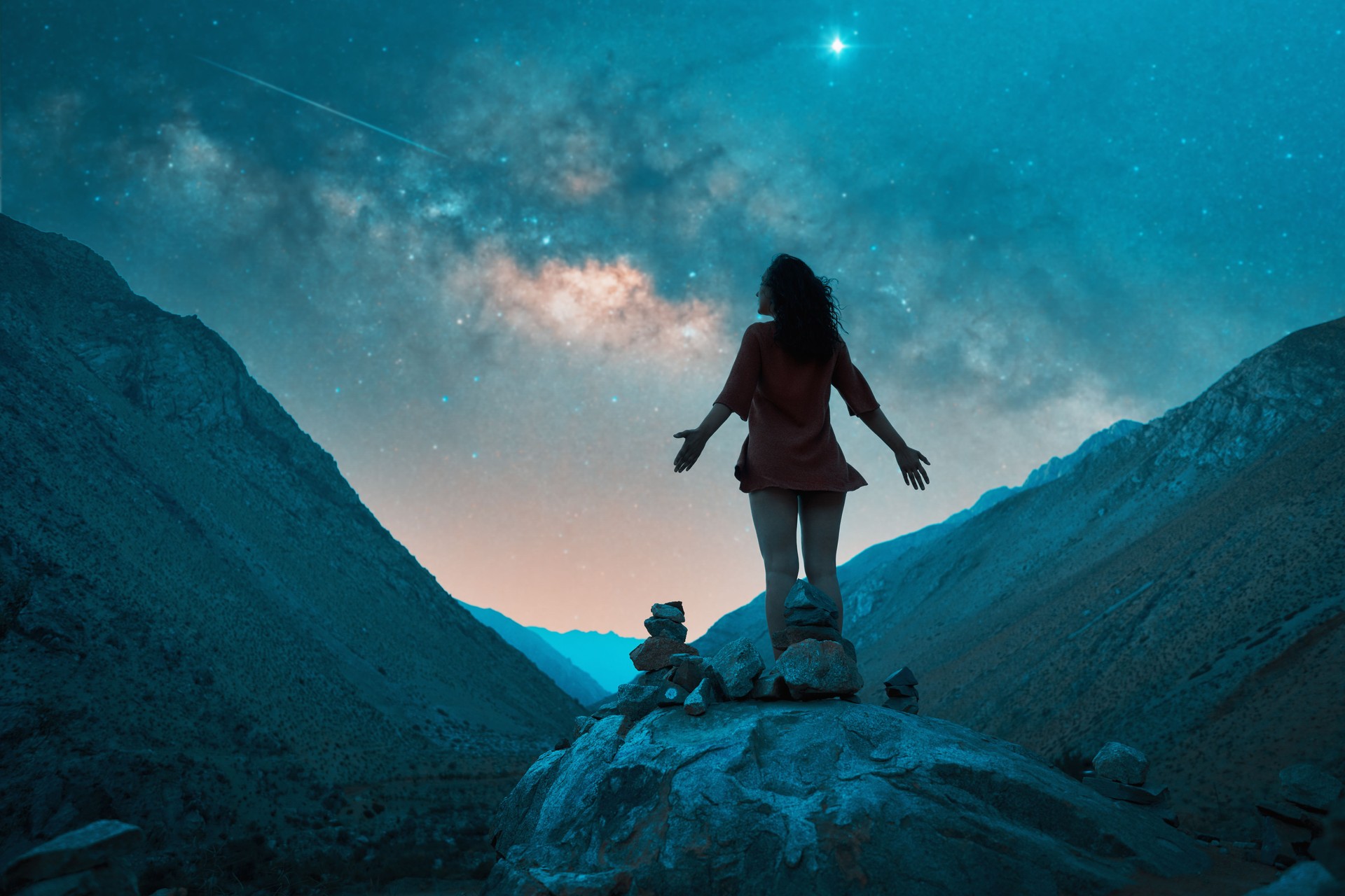 silhouette of a woman on a rock between the hills at night with the milky way and stars in the background